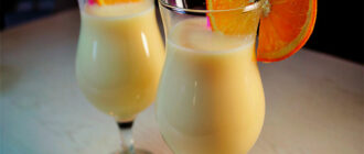 банановый молочный коктейль в бокале с долькой апельсина